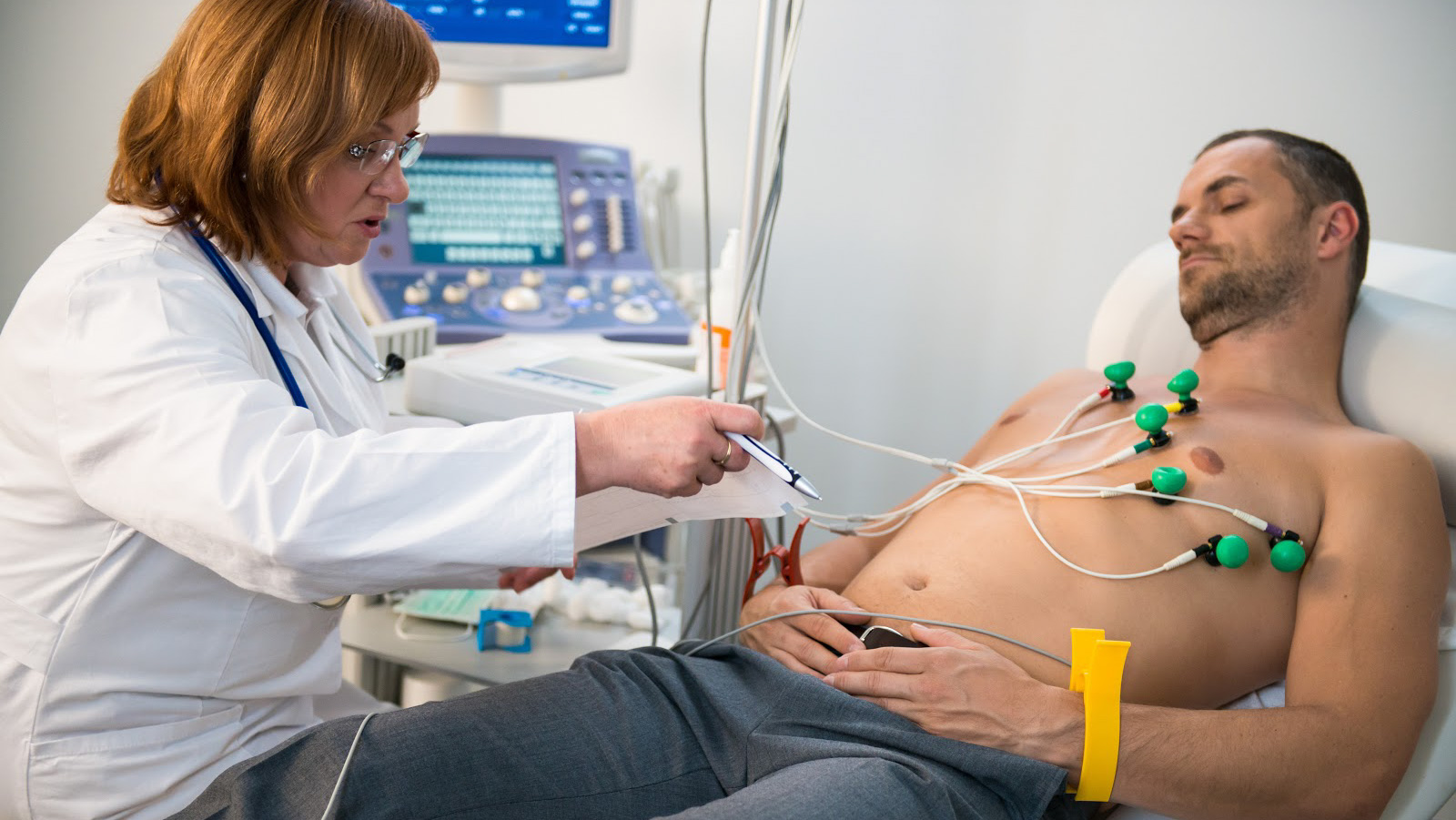 Female doctor makes the patient ready for EKG test.